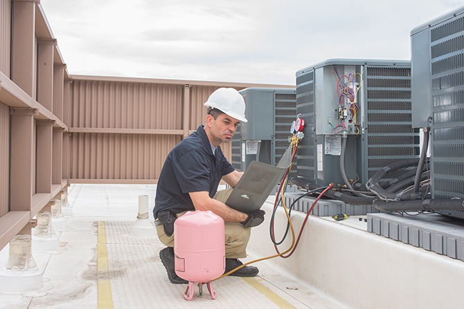 Technician looking at a panel off a condensing unit Why Choose Us